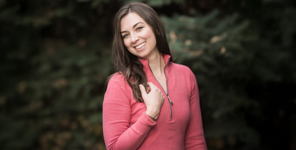 Woman smiling outside in a salmon athletic jacket in the afternoon