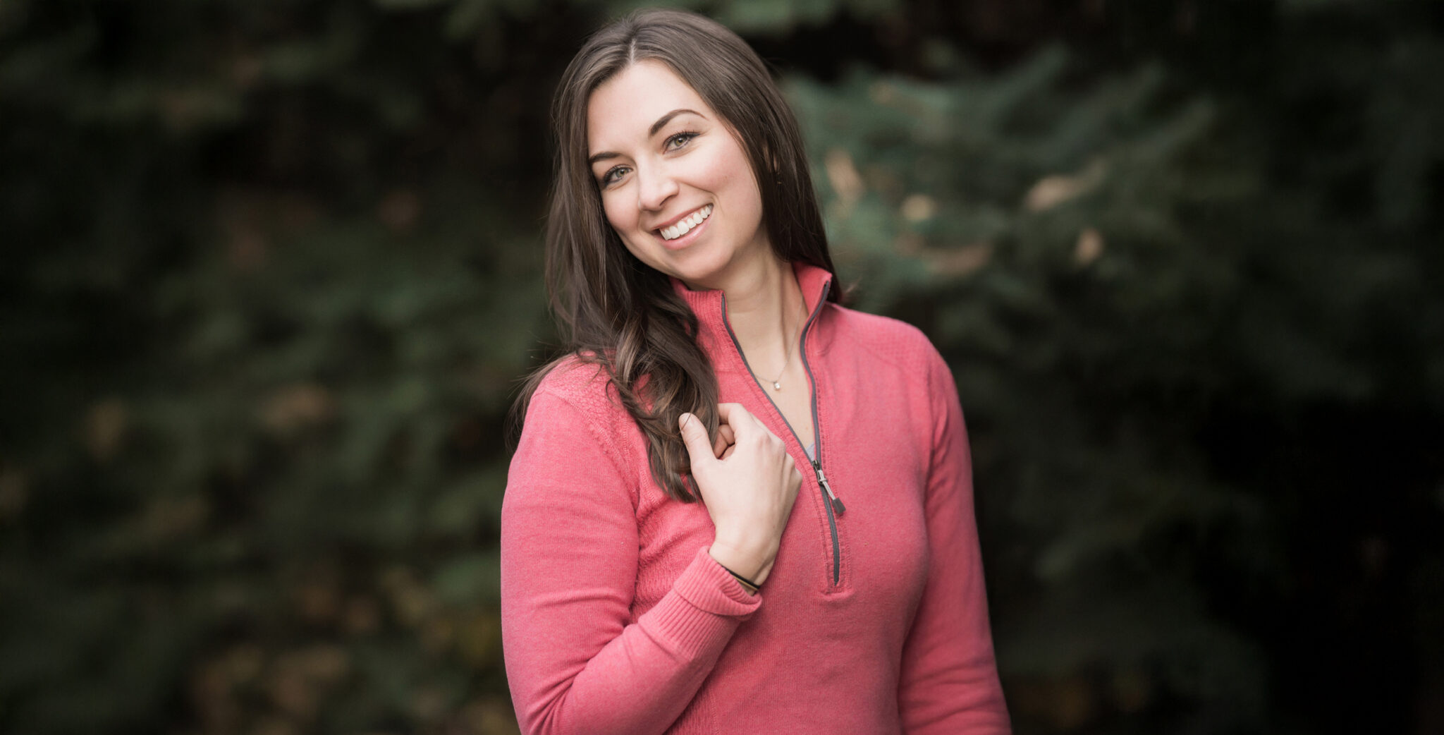 Woman smiling outside in a salmon athletic jacket in the afternoon
